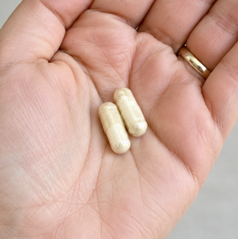 Two ORALEA capsules in an open palm.